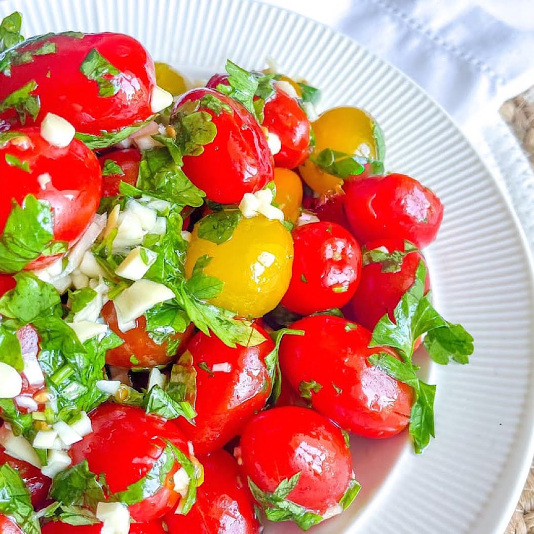 Close-up of multicolour cherry tomatoes coated in herb vinaigrette.