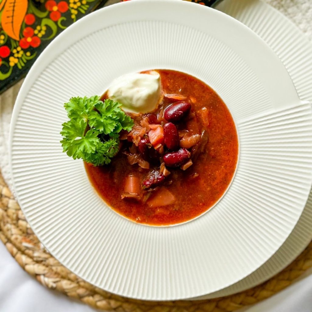 Overhead view of vegetarian red kidney beans borscht with beans and sour cream