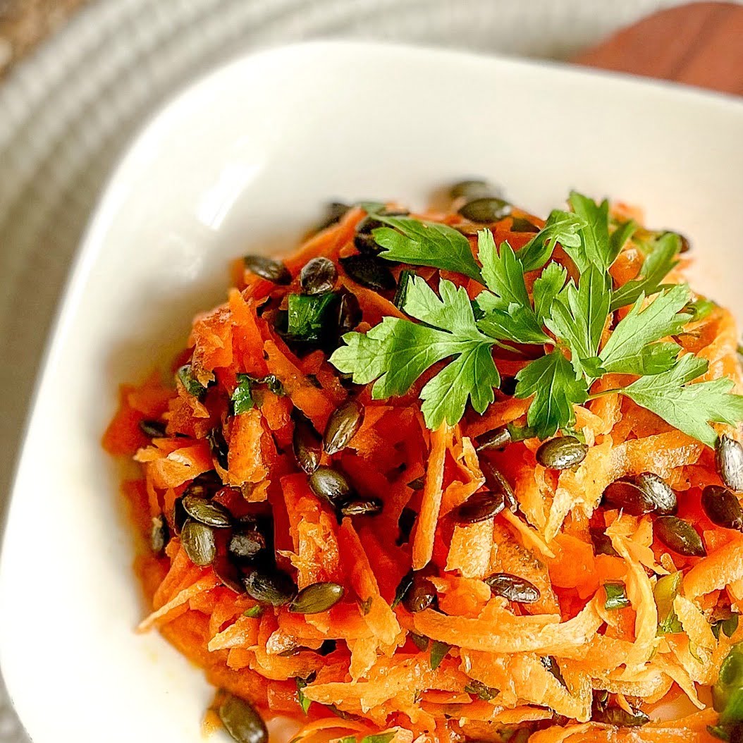 Easy carrot and parsley salad recipe served in a square white dish with parsley garnish.