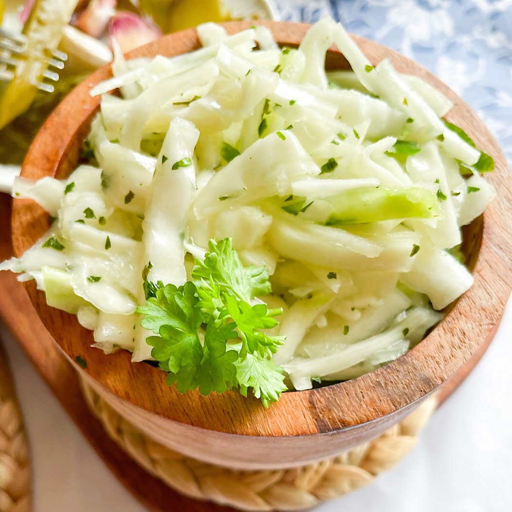 Russian cabbage salad ingredients – chopped green cabbage, cucumber, parsley and spring onions close-up