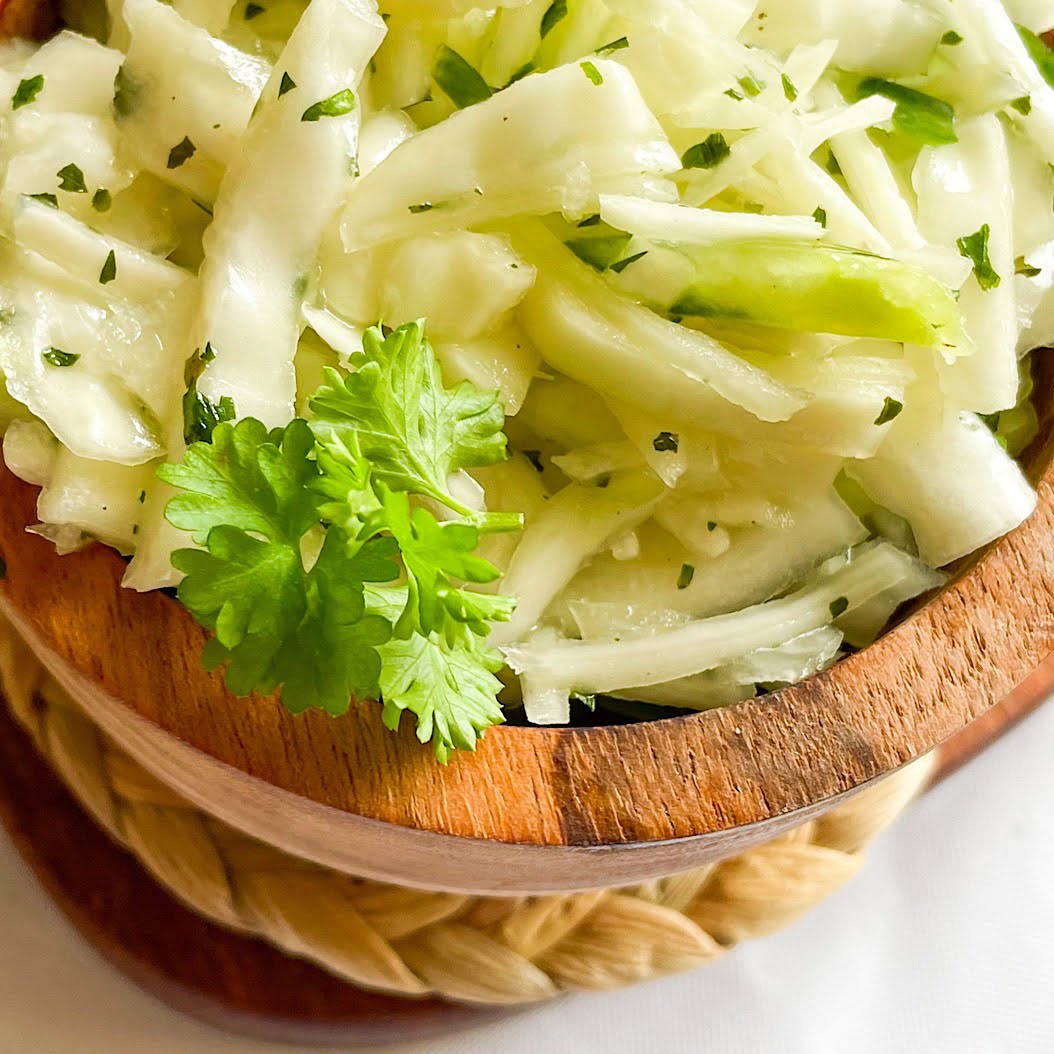 Traditional Russian cabbage salad served with pickles in a rustic wooden bowl