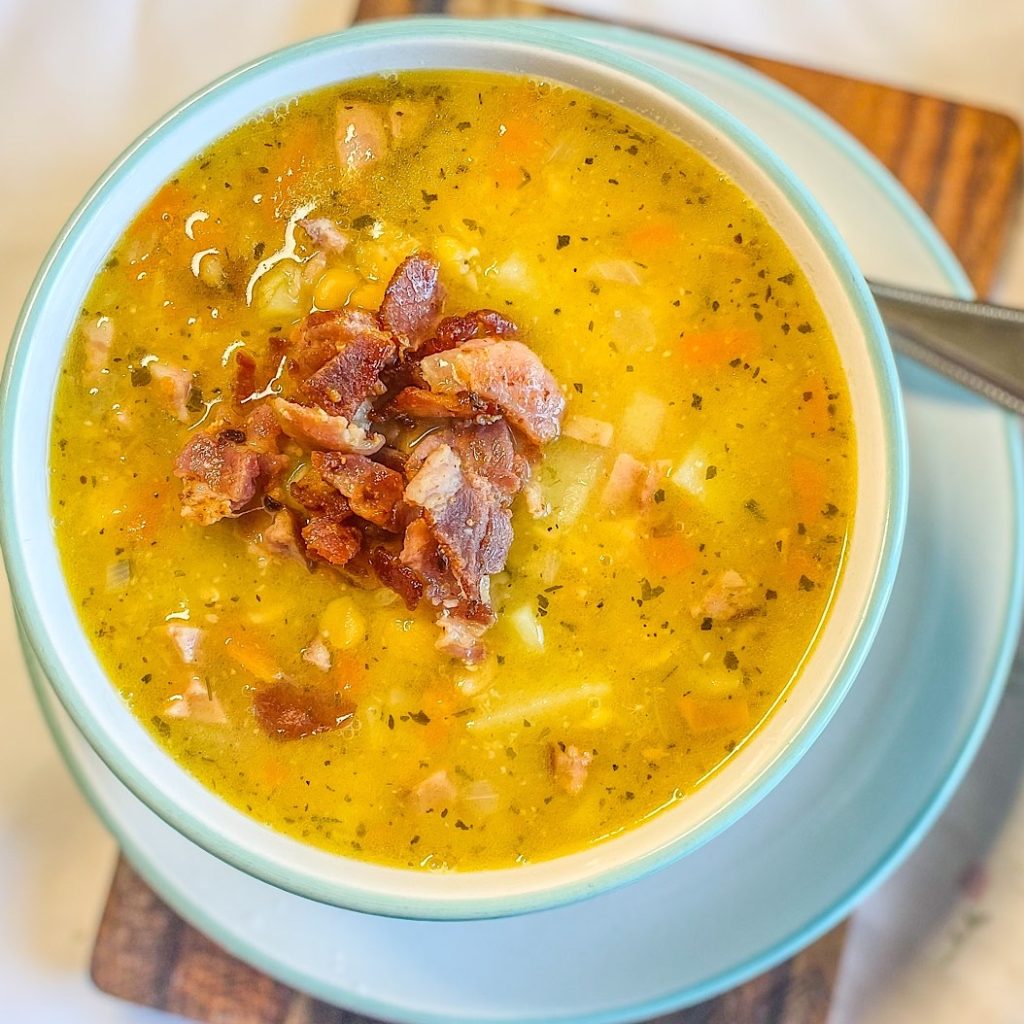 Hearty Smoked Split Pea Soup topped with crispy bacon in a blue bowl, close-up overhead shot