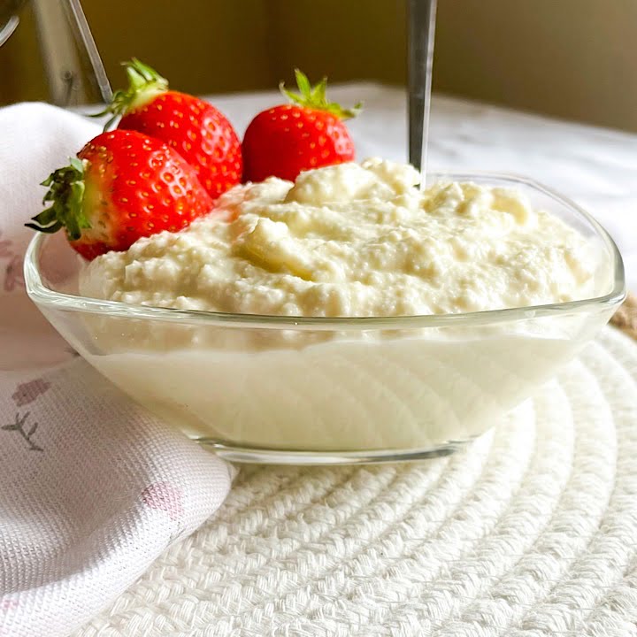 Close-up of creamy homemade cottage cheese with strawberries on a woven mat