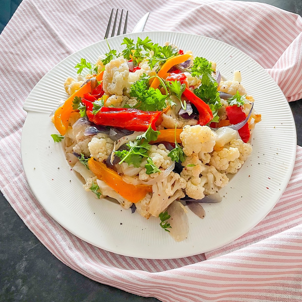 Healthy roasted cauliflower salad with mixed peppers and fresh flat-leaf parsley on top