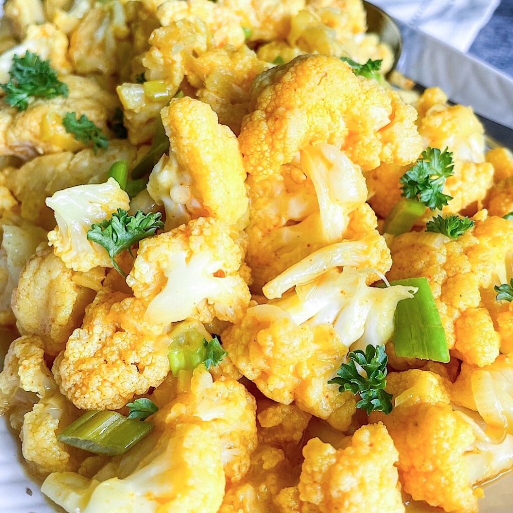 Close-up of cooked cauliflower in coconut milk with turmeric and parsley garnish