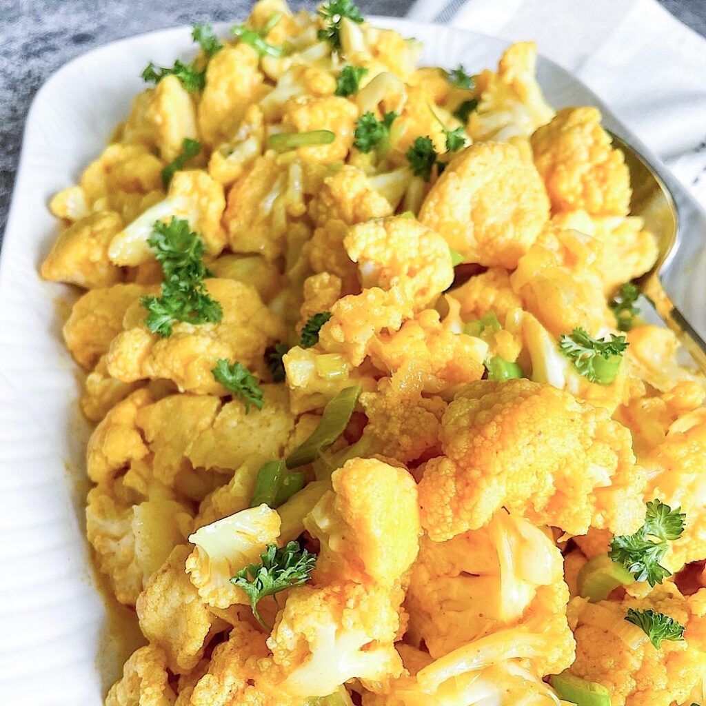 Plated cauliflower in coconut milk with creamy sauce and fresh herbs