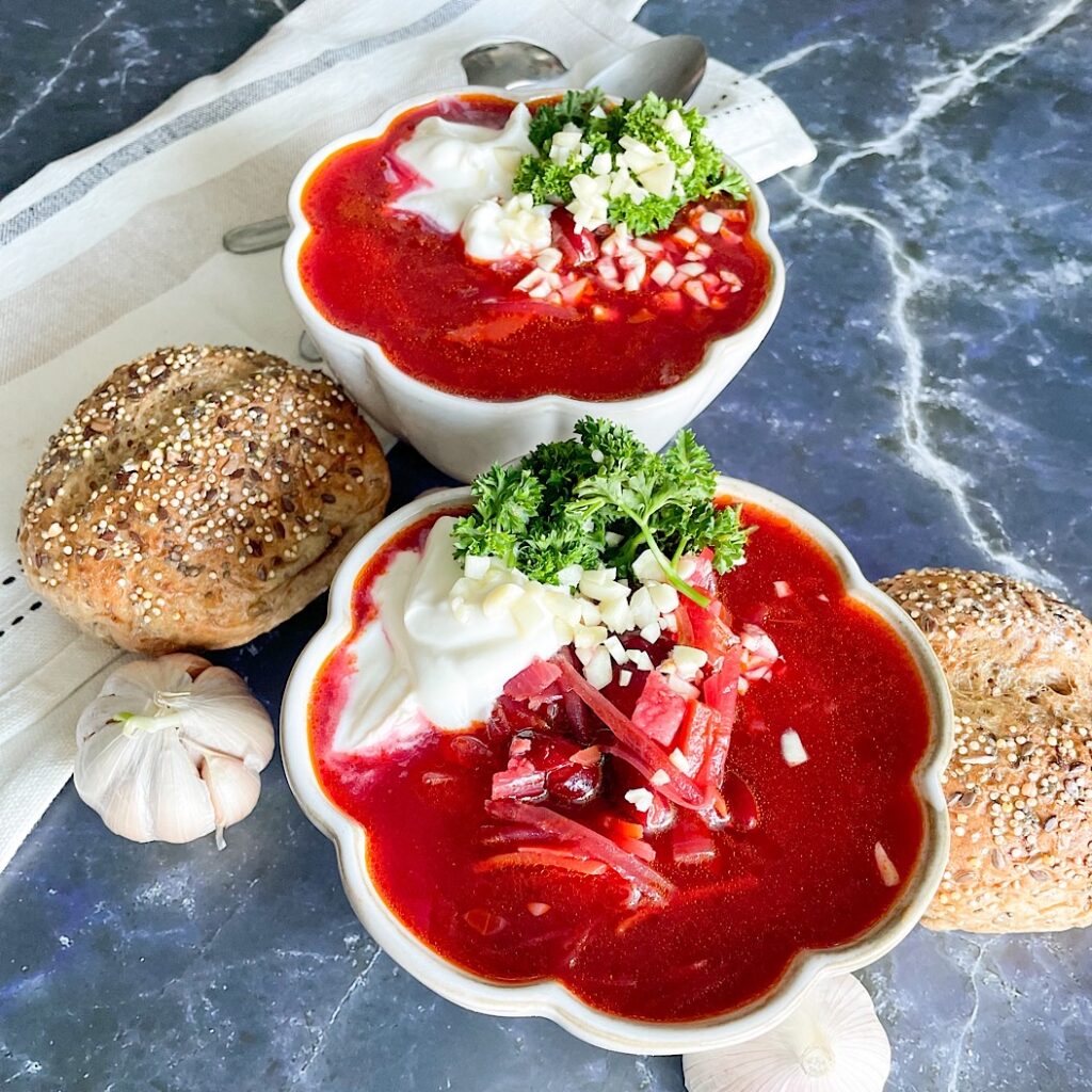 Easy beetroot soup recipe with beans, sour cream and fresh parsley served with bread and garlic