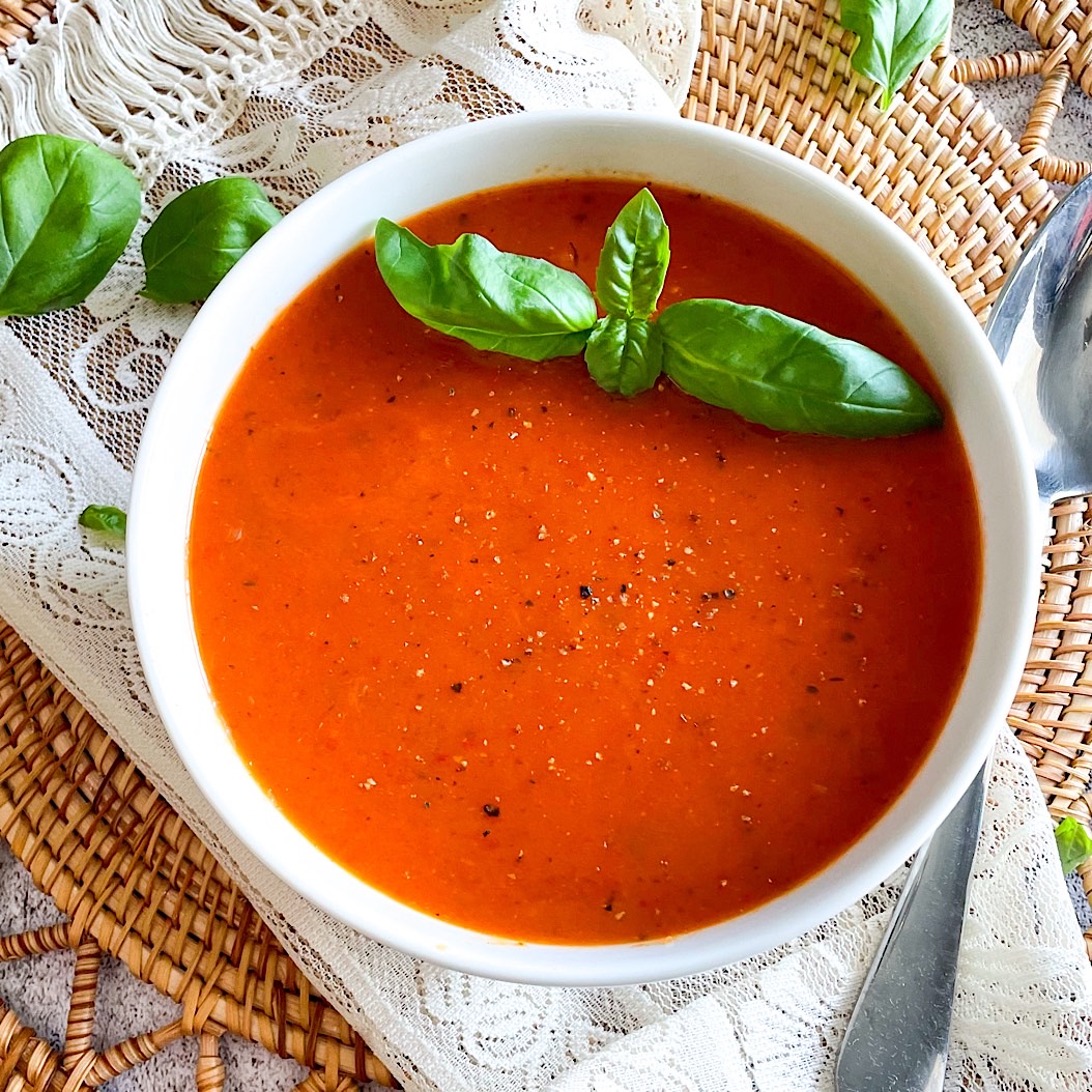 Creamy Roasted Pepper Soup in a white bowl, garnished with fresh basil