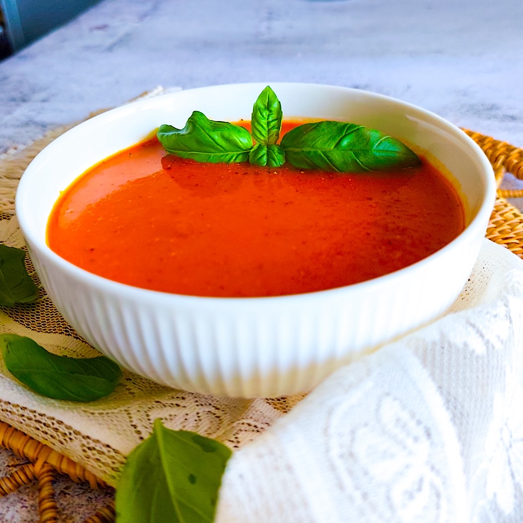 Creamy Roasted Pepper Soup in a white bowl, garnished with fresh basil