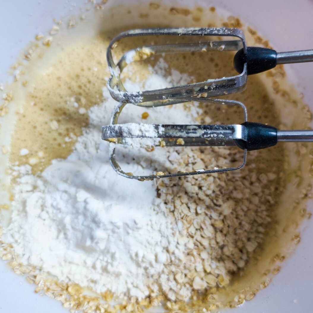 Flour and rolled oats added to whisked egg for apricot oatmeal cookies