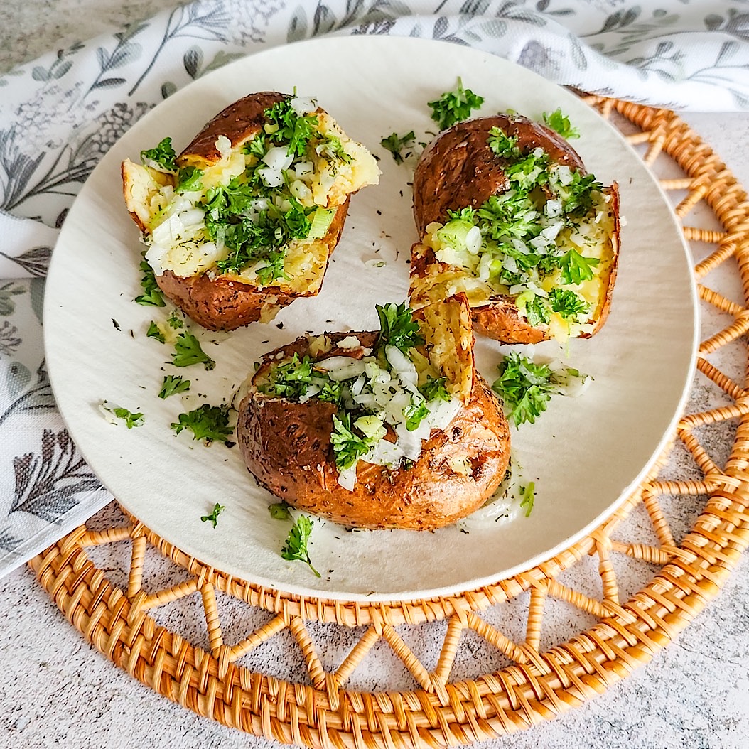 Overhead shot of herbed baked potatoes with parsley and onions.