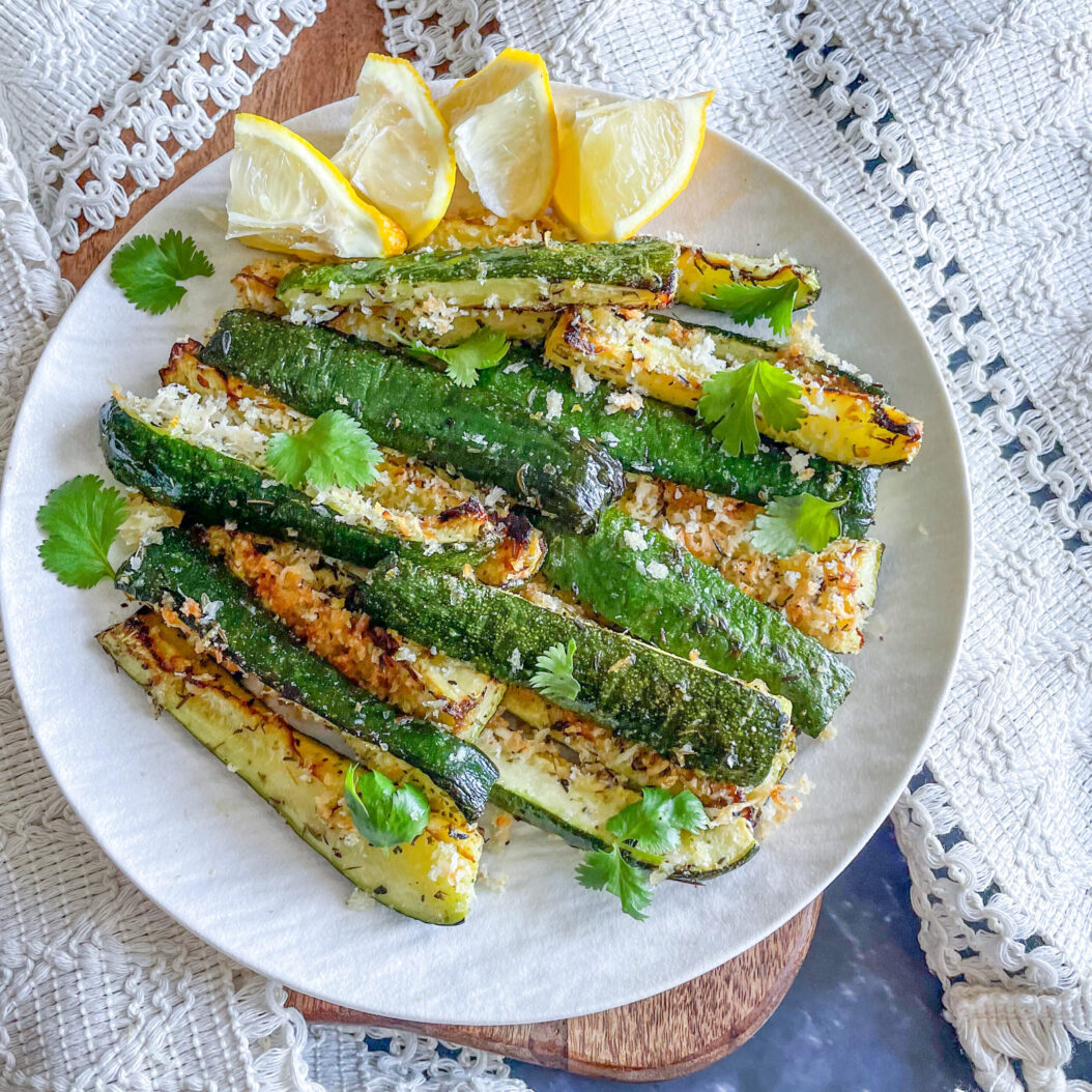 Oven roasted courgettes with parmesan, lemon zest and coriander on a serving plate