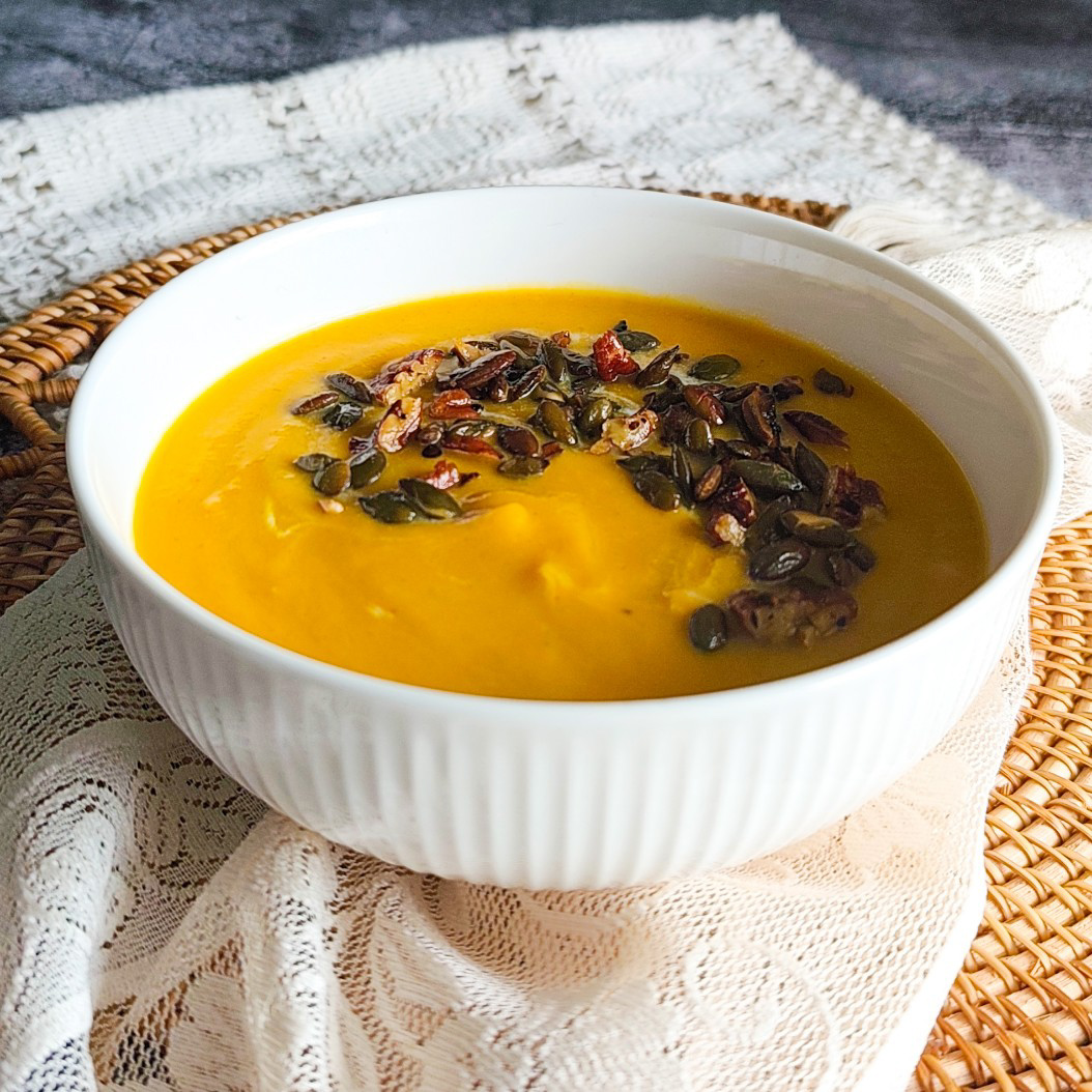 Warm and silky butternut squash soup served with spiced crunchy topping on rustic lace napkin