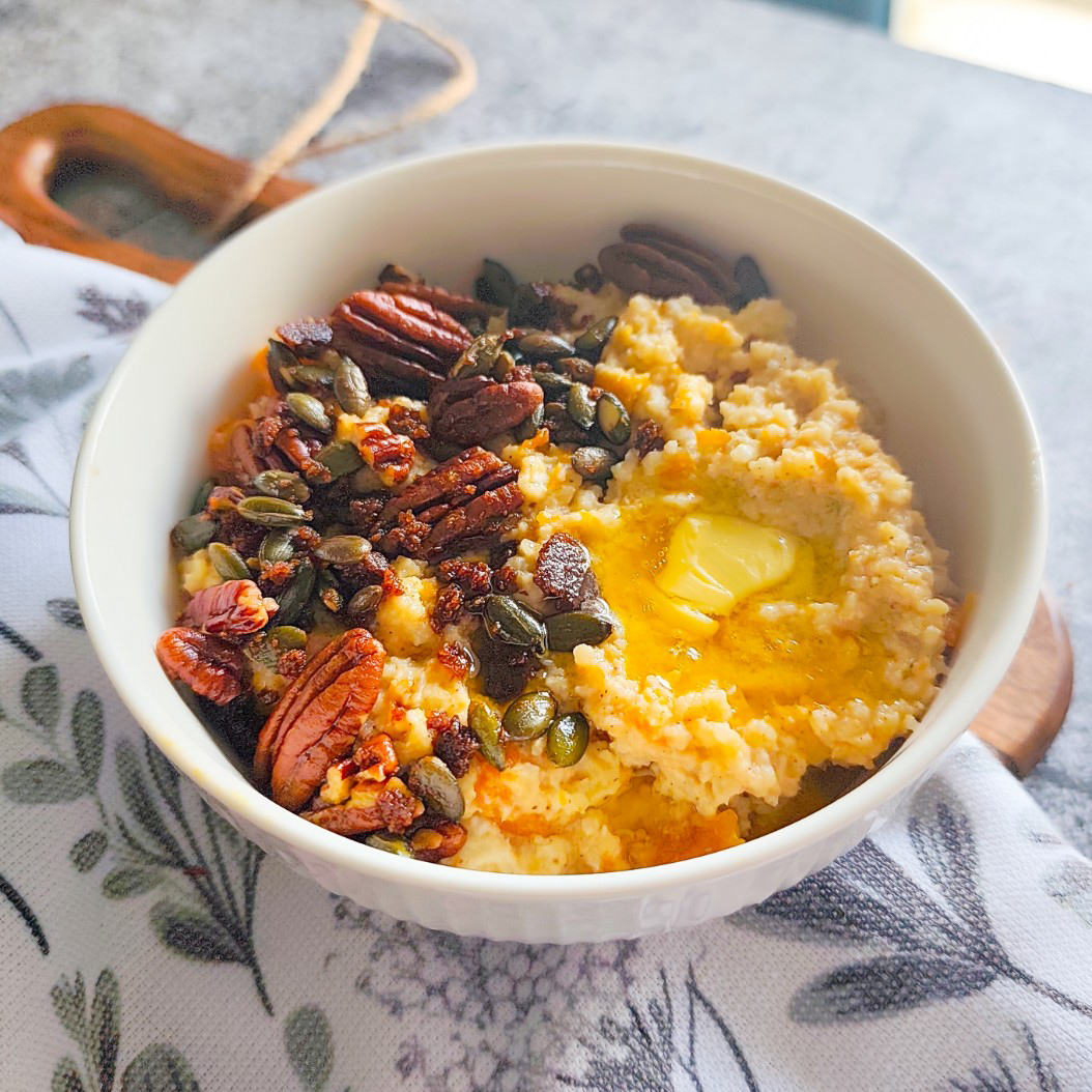 Creamy pumpkin millet porridge with cinnamon butter and crunchy nut topping served in a white bowl
