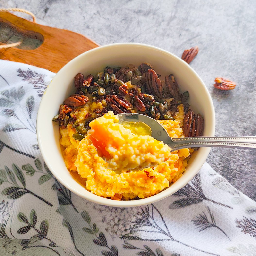 Spoonful of pumpkin millet porridge showing creamy texture and a chunk of pumpkin