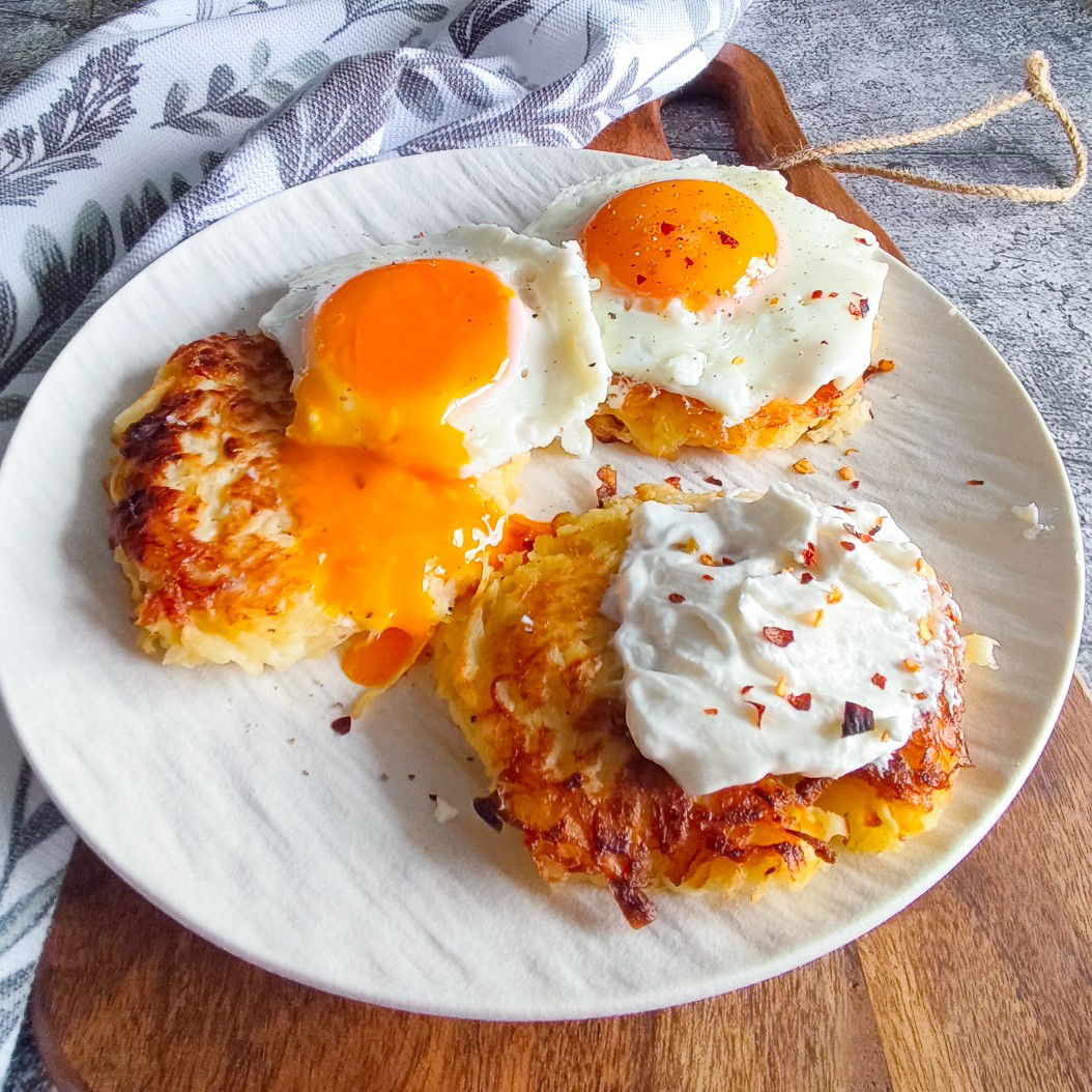 Low-carb celeriac rösti served hot on a white plate with fried eggs