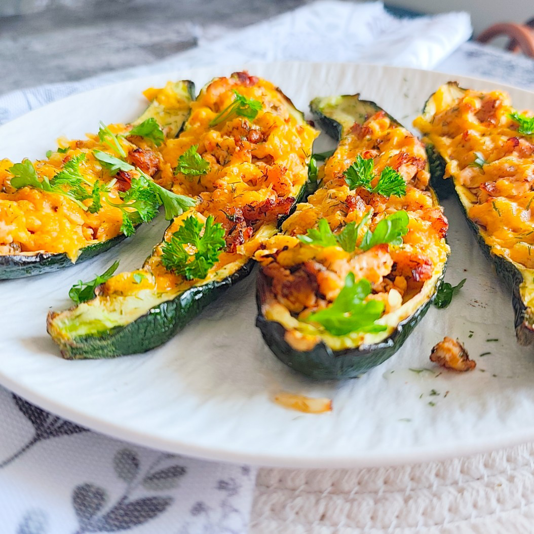 Cheesy turkey courgette boats in a baking dish with melted cheddar.