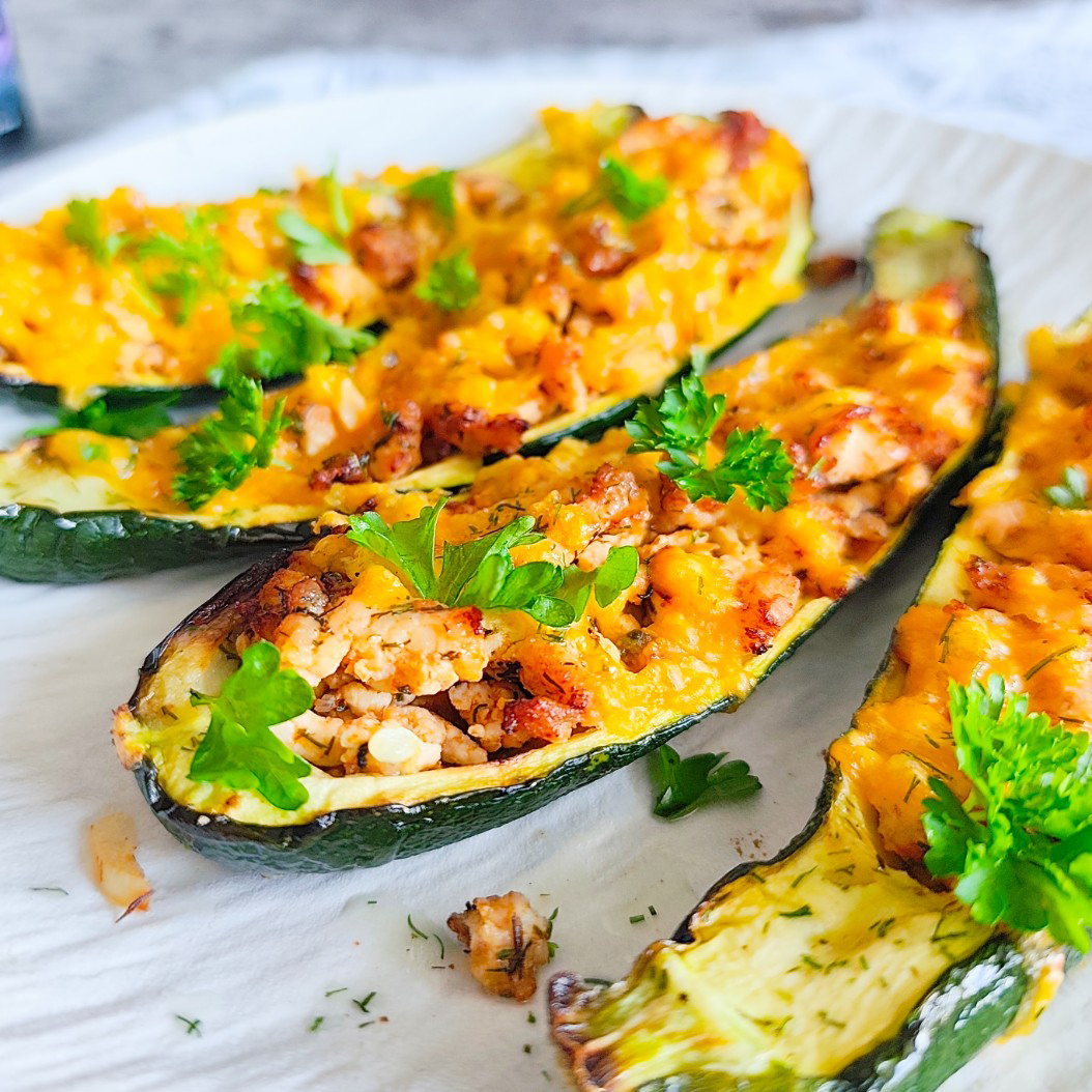 Close-up of golden-baked turkey courgette boats with fresh parsley.