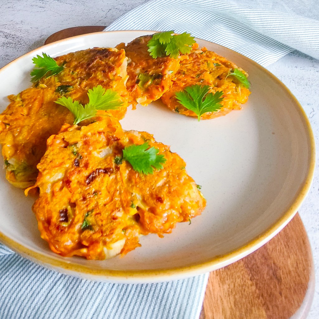 crispy carrot fritters on a cream plate garnished with fresh herbs, ideal vegetarian lunch or snack idea