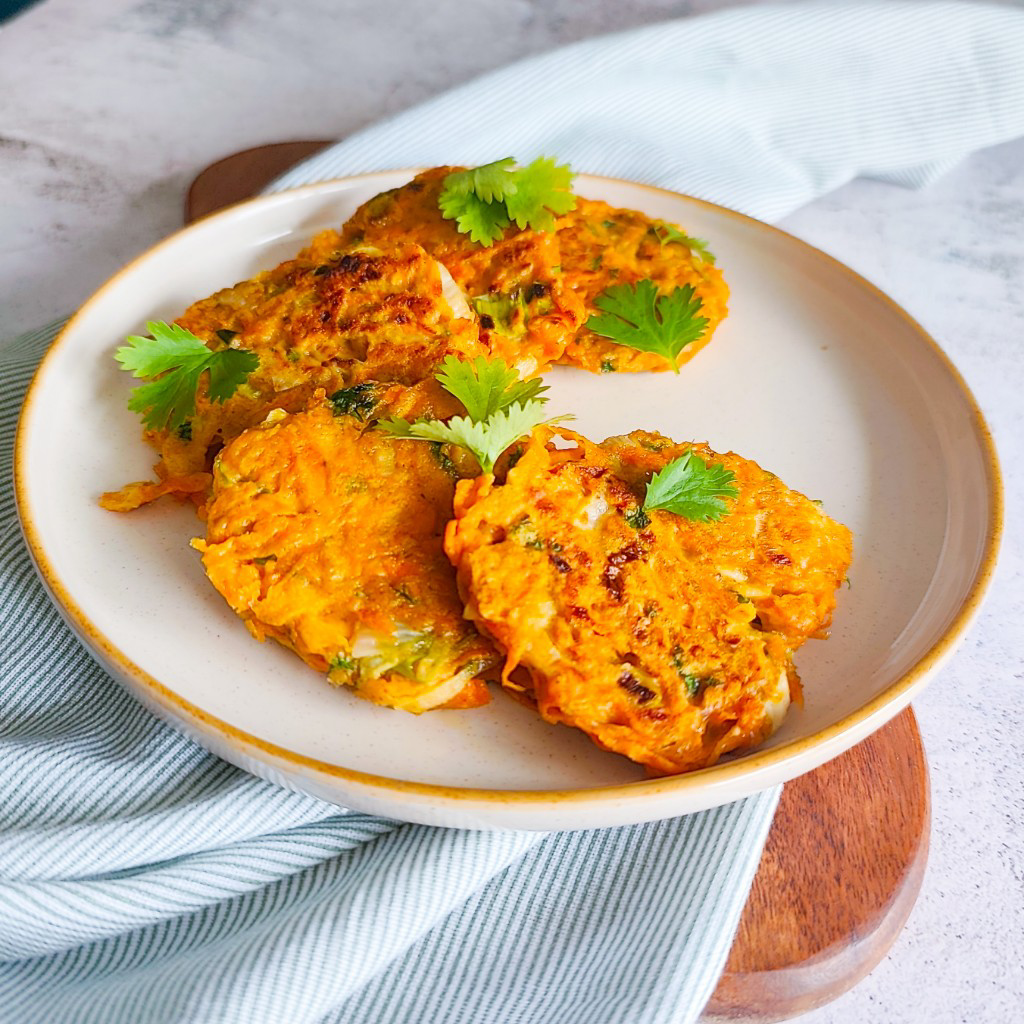 golden carrot fritters arranged on a plate, ready to serve with fresh parsley on top and soft natural lighting