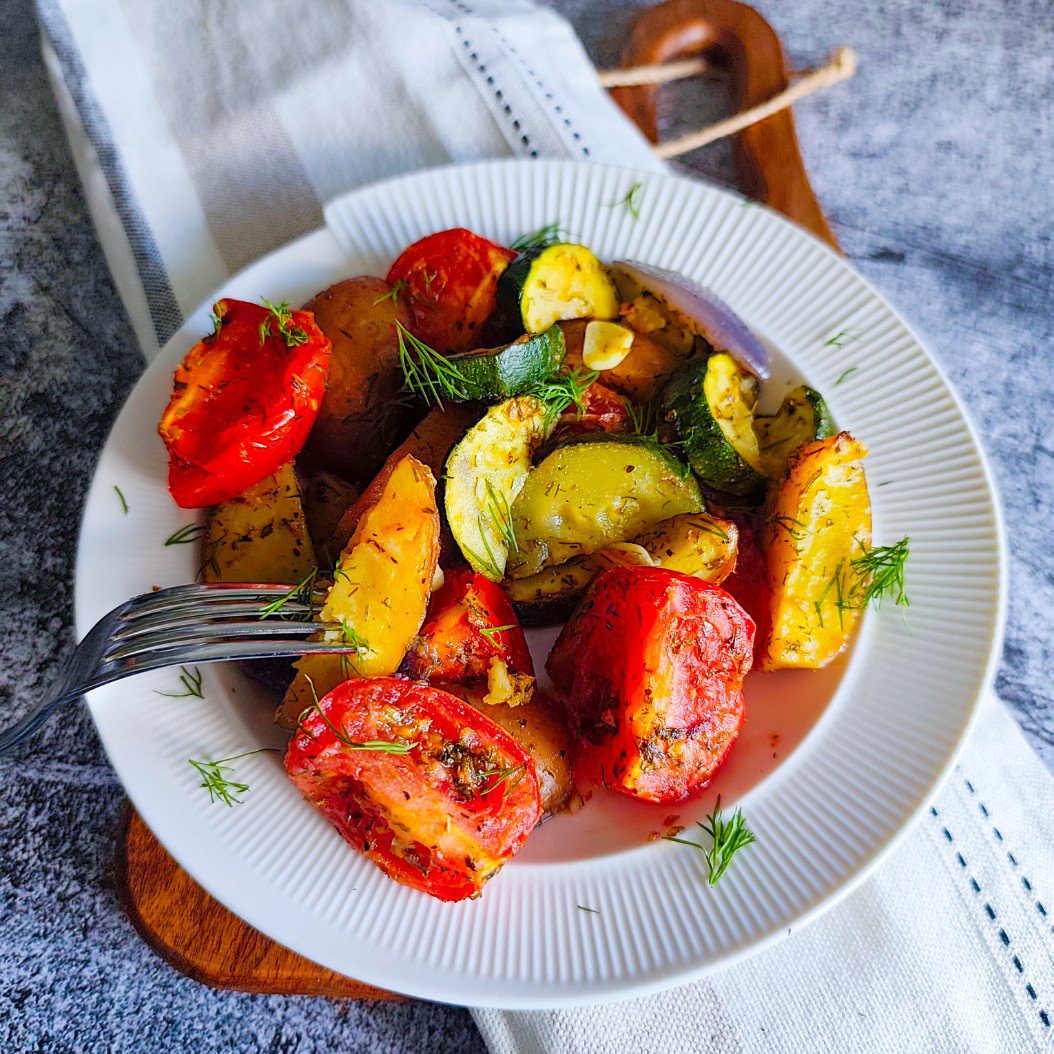 Close-up of colourful roasted vegetables with tomatoes, courgettes, and potatoes.
