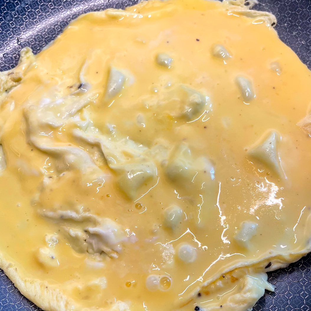 Beaten eggs cooking gently in a skillet for mushroom omelette base.