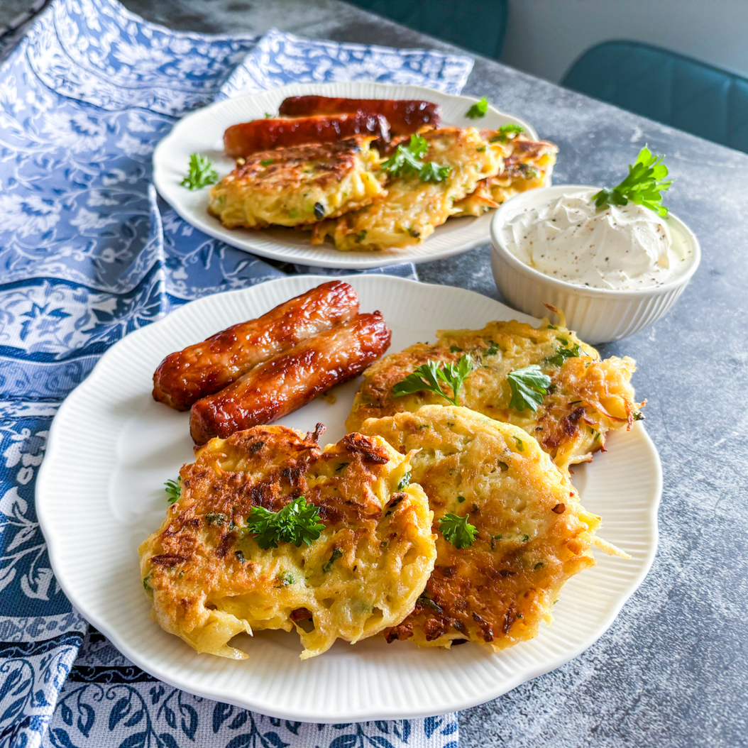 Crispy parsnip fritters and sausages on a plate with yoghurt sauce, ready to serve.