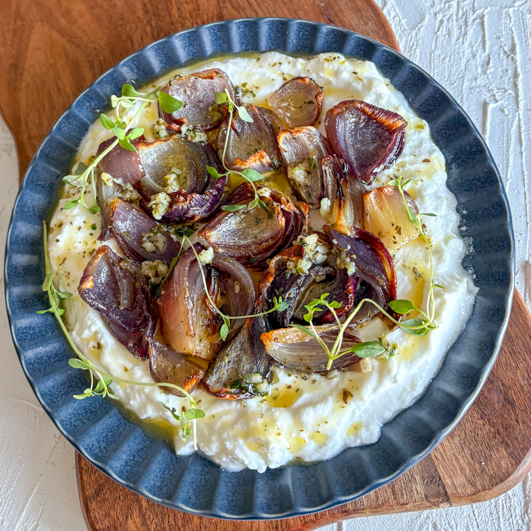 Roasted red onions arranged over ricotta, drizzled with herb-infused butter and fresh thyme leaves.