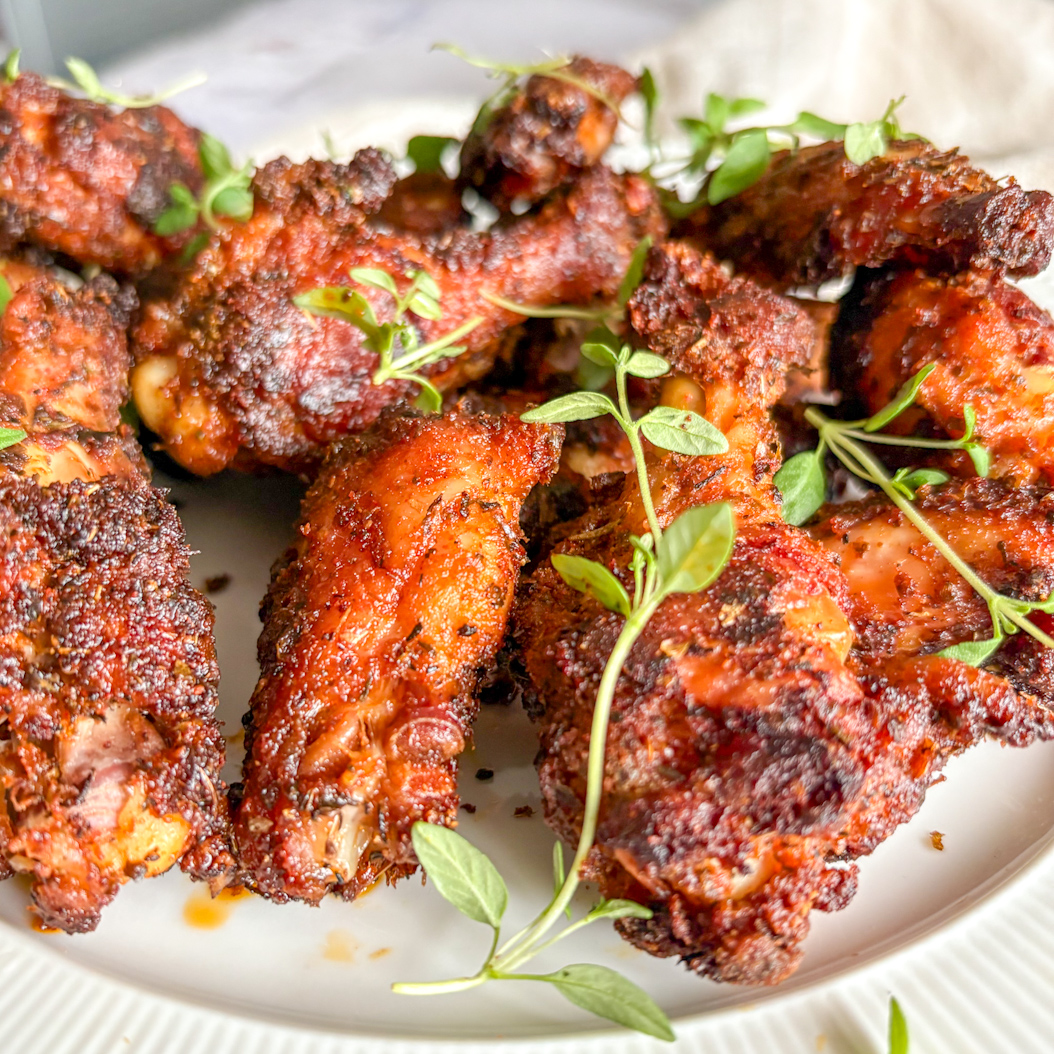 Golden, crispy Creole Chicken Wings served on a plate with fresh thyme sprigs.