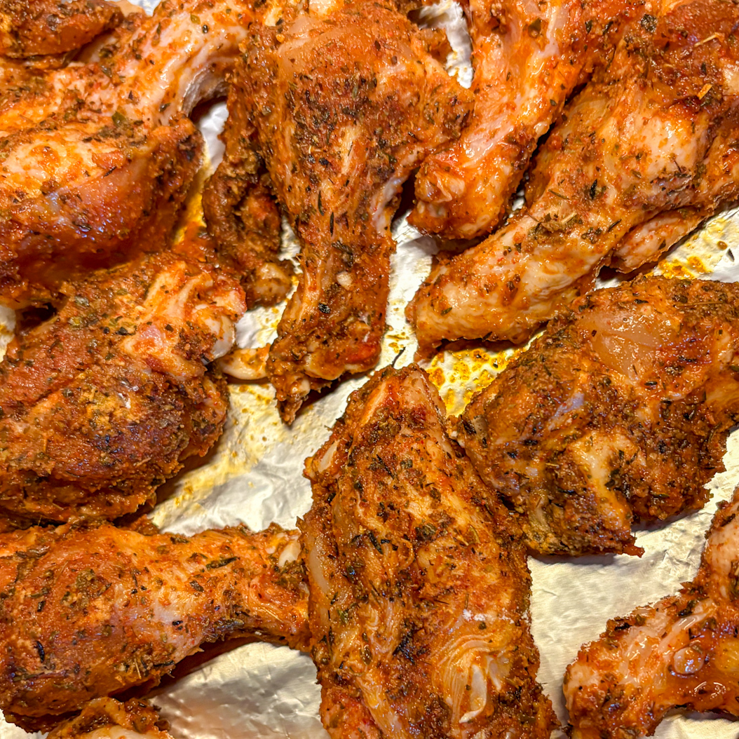 Creole Chicken Wings placed on a foil tray before roasting in the oven.