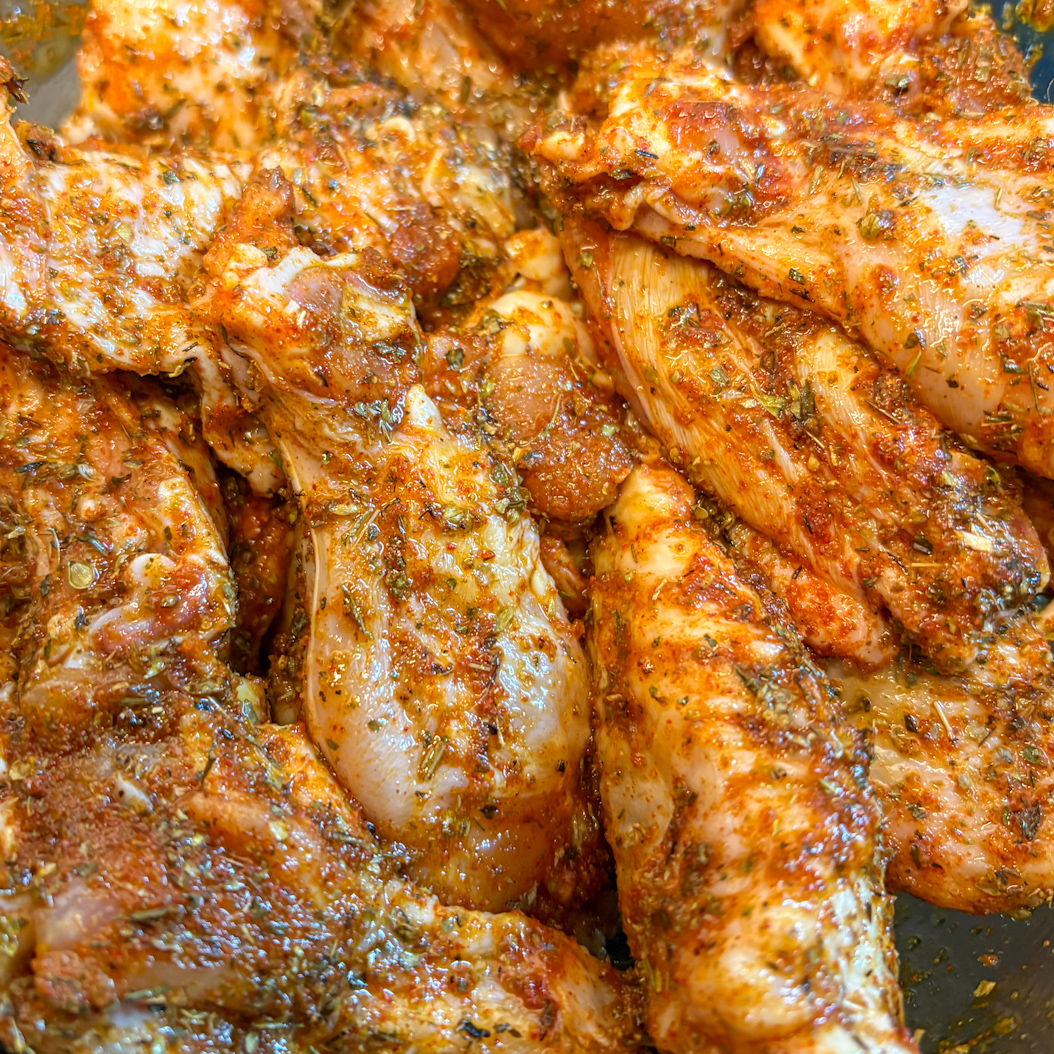 Marinated chicken wings coated in Creole herbs and spices before baking.