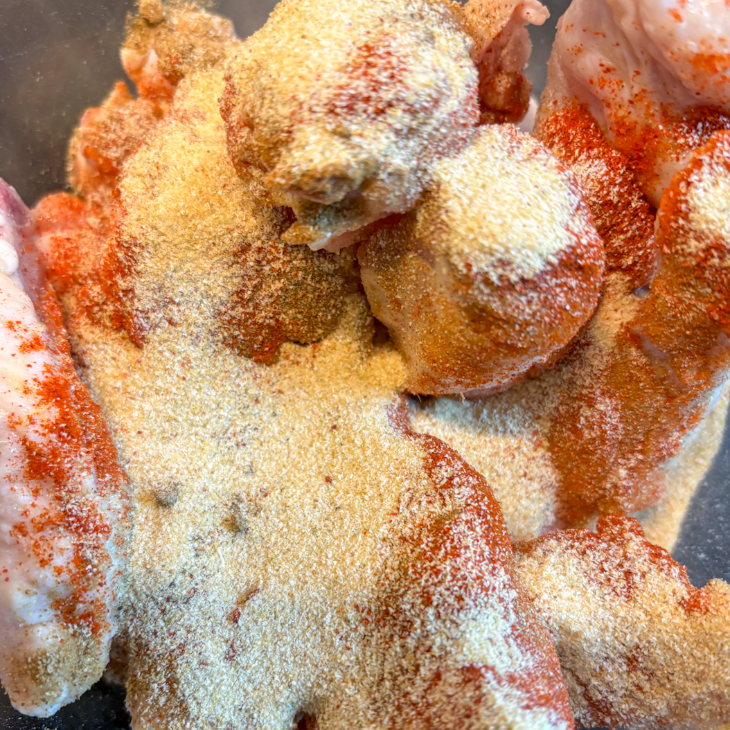 Raw chicken wings coated with paprika and garlic powder for Creole Chicken Wings seasoning.
