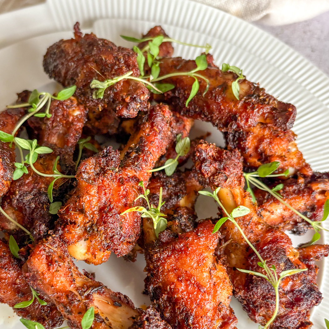 Close‑up of spicy, oven‑baked Creole Chicken Wings with crispy skin and herbs.
