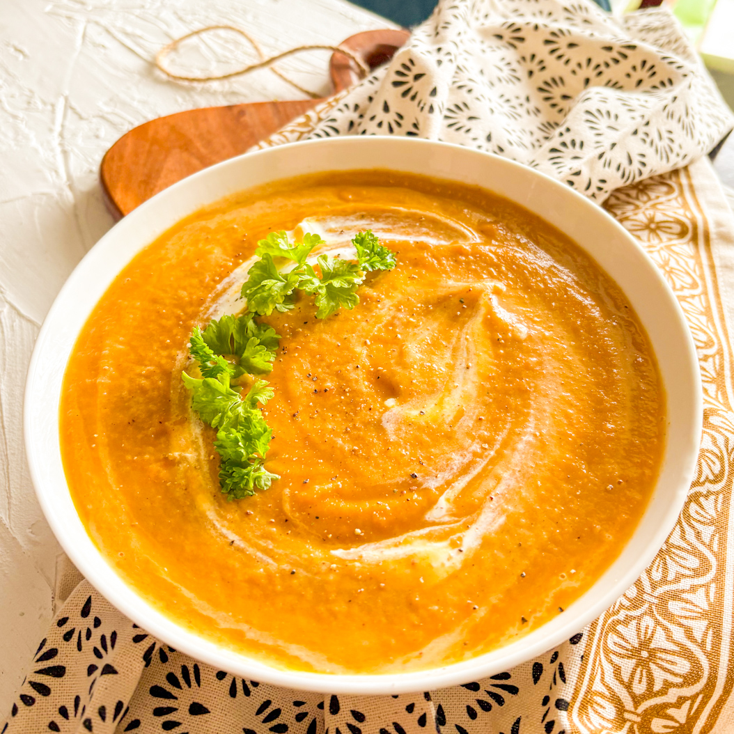 Smooth spiced carrot soup garnished with parsley and cracked black pepper