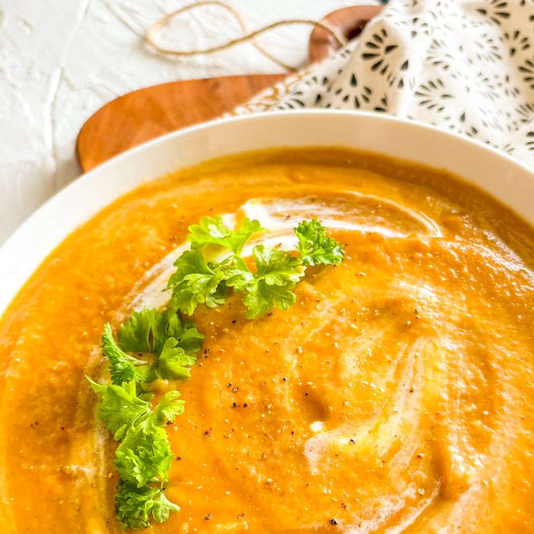 Close-up of spiced carrot soup with cream swirl and fresh parsley