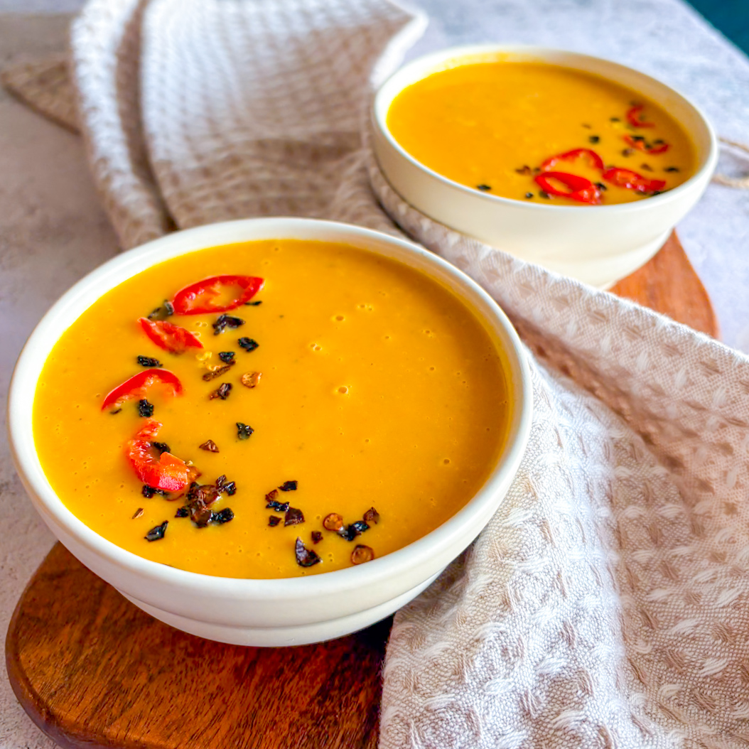 Close-up of Sweet Potato and Carrot Soup with red chilli and cracked pepper topping