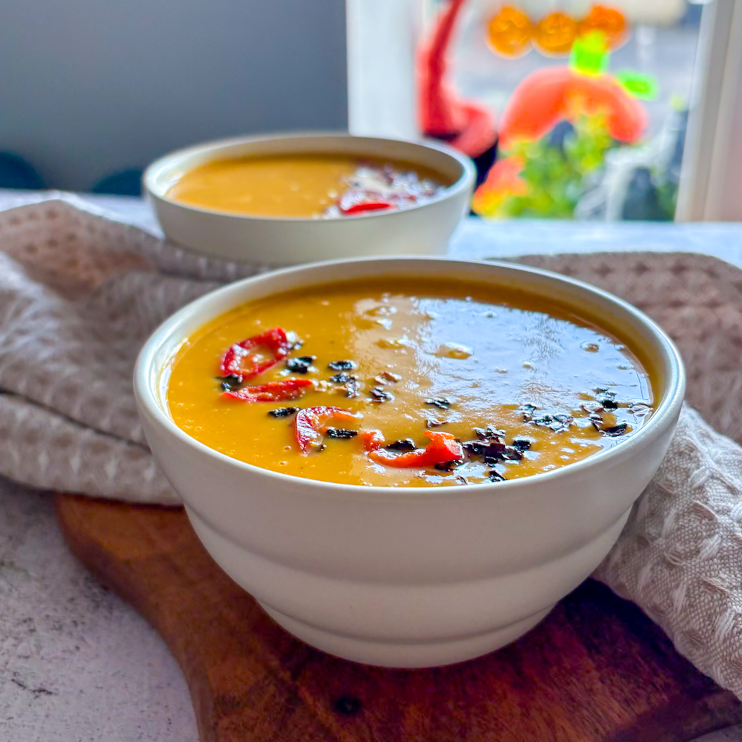 Sweet Potato and Carrot Soup in white bowls topped with chilli flakes and fresh red chilli slices