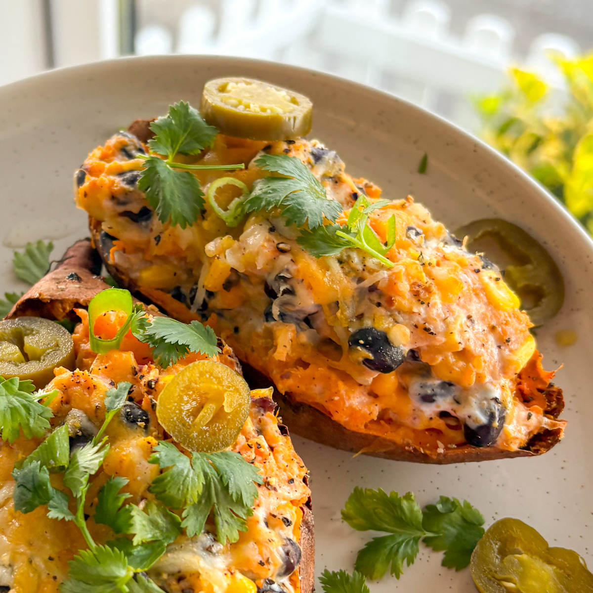 Close-up of loaded sweet potatoes with creamy filling, black beans, corn and melted cheese