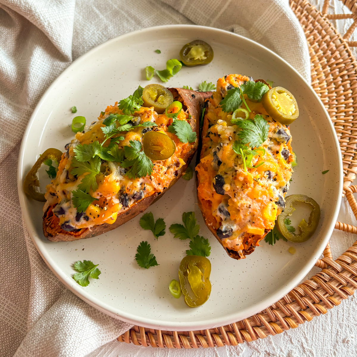Loaded sweet potatoes with black beans, corn, melted cheese, jalapeños and fresh coriander on a plate