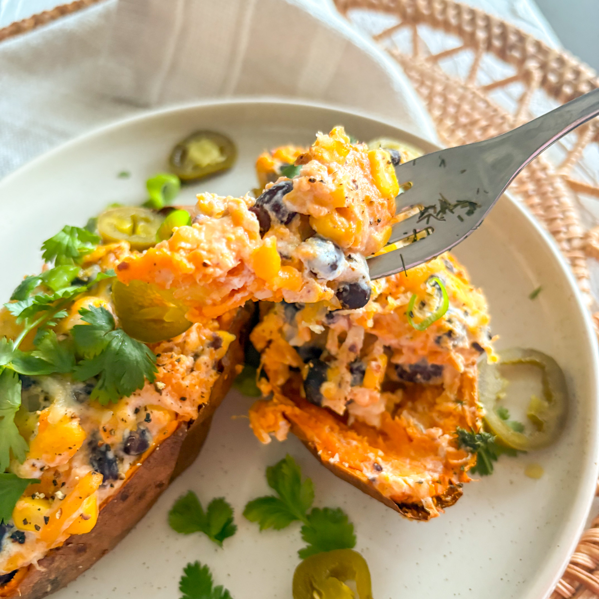 Bite of loaded baked sweet potatoes showing creamy mash, beans, corn and melted cheese texture