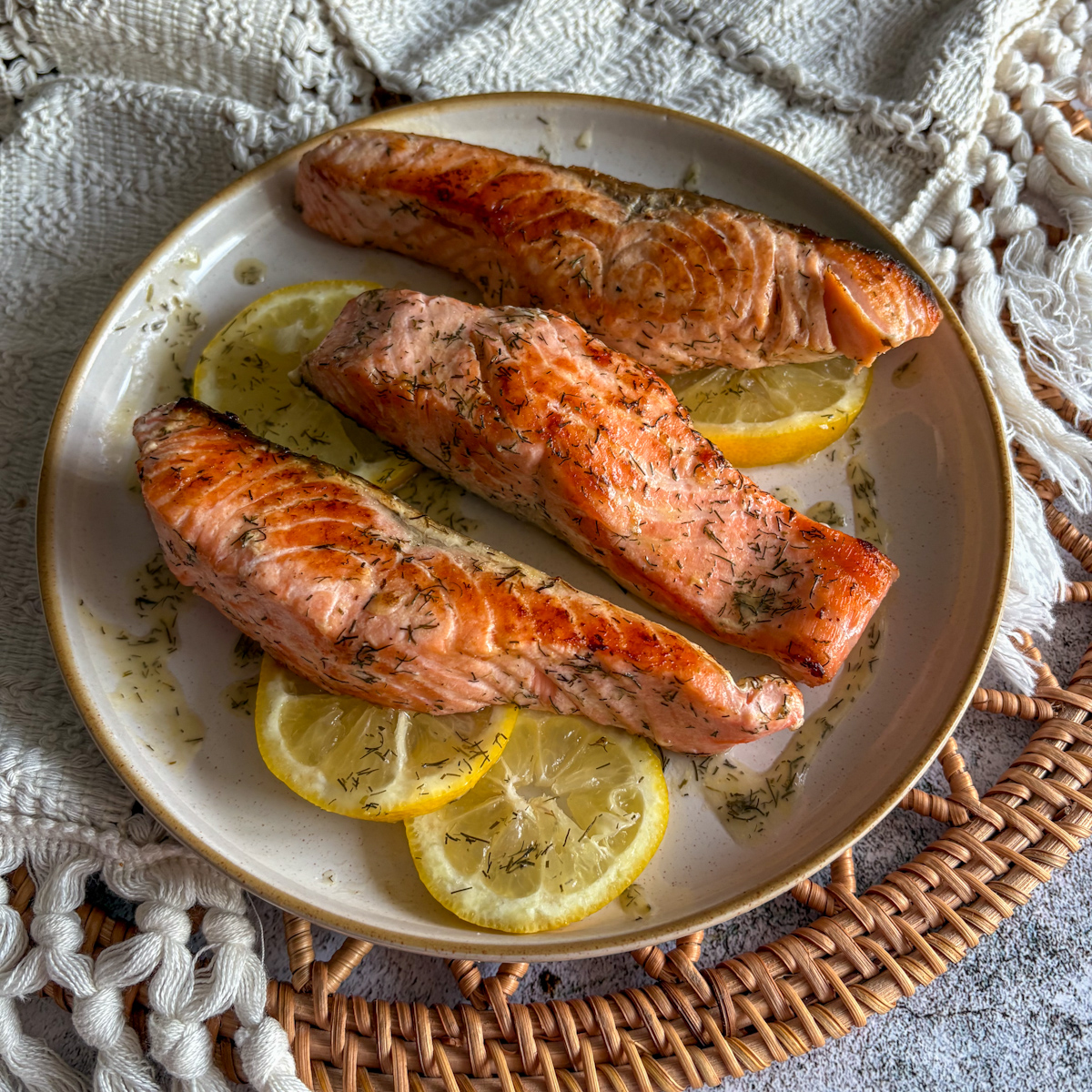 Three perfectly cooked pan fried salmon portions showcasing a flaky texture and a glossy lemony butter glaze, arranged neatly for a healthy lunch option.