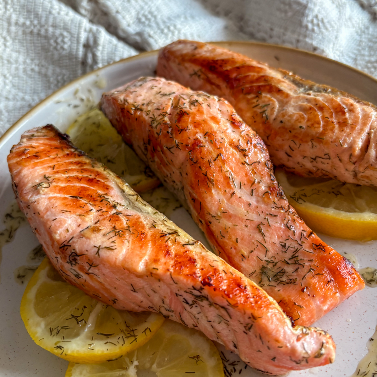 Detailed view of a pan fried salmon fillet with a golden-brown crust and vibrant pink interior, highlights the success of effortless cooking on a skillet.