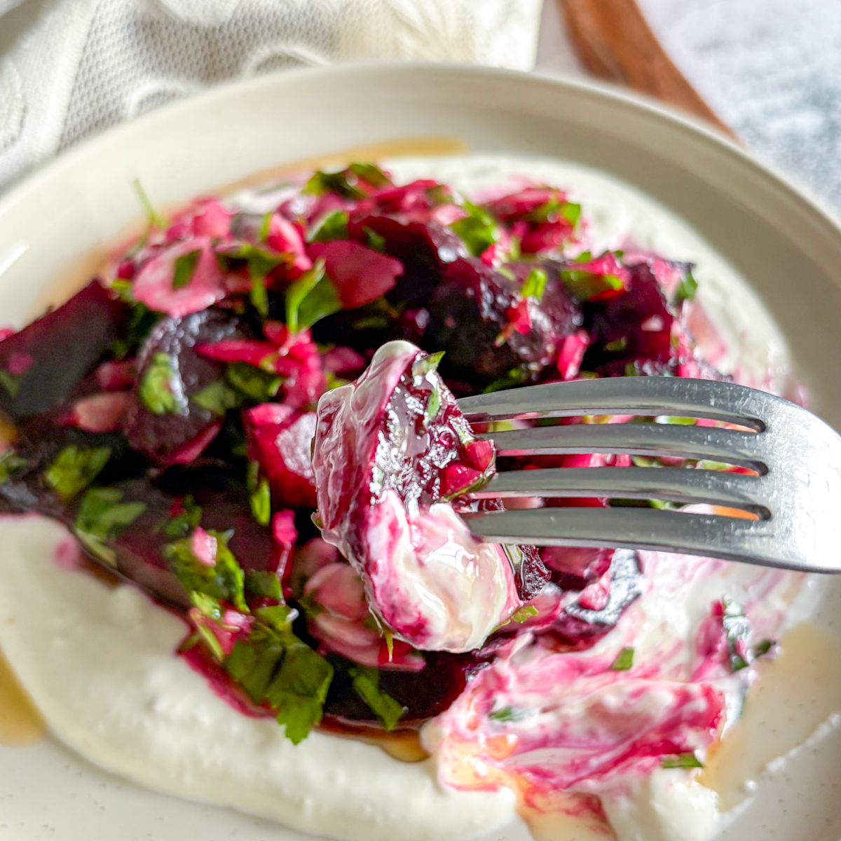 Fork lifting roasted beet salad with sour cream, highlighting creamy texture and earthy flavour