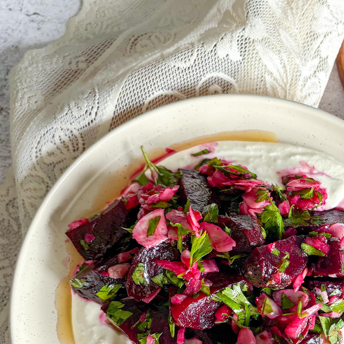 Roasted beet salad with sour cream and horseradish, topped with fresh herbs and almonds in a rustic bowl