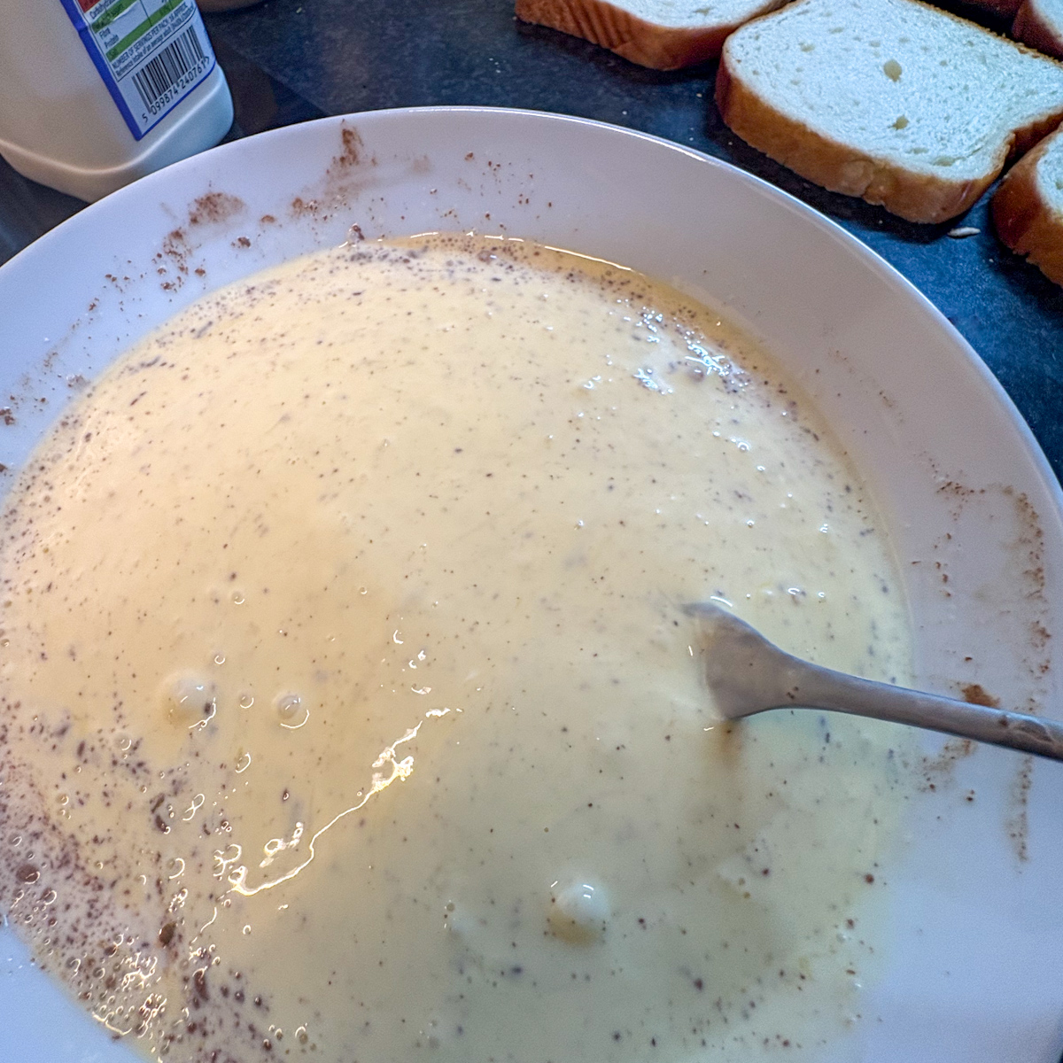 Whisking together large eggs, double cream, and ground cinnamon in a shallow bowl to start this easy homemade brioche French toast recipe.