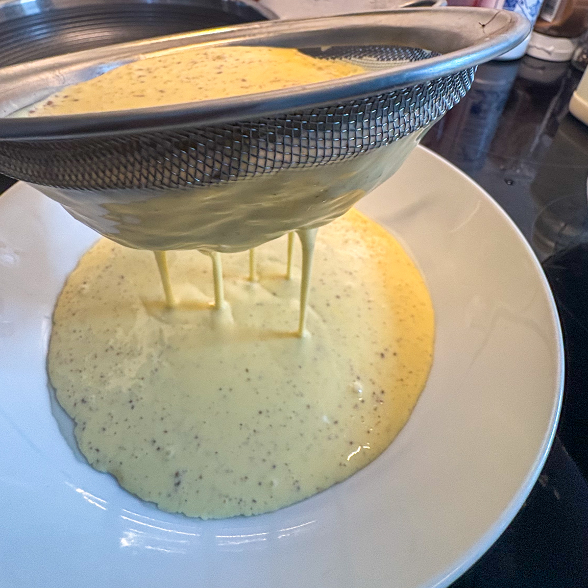 Using a fine mesh strainer to strain the mixture, ensuring a delicately silky and smooth custard French toast recipe.