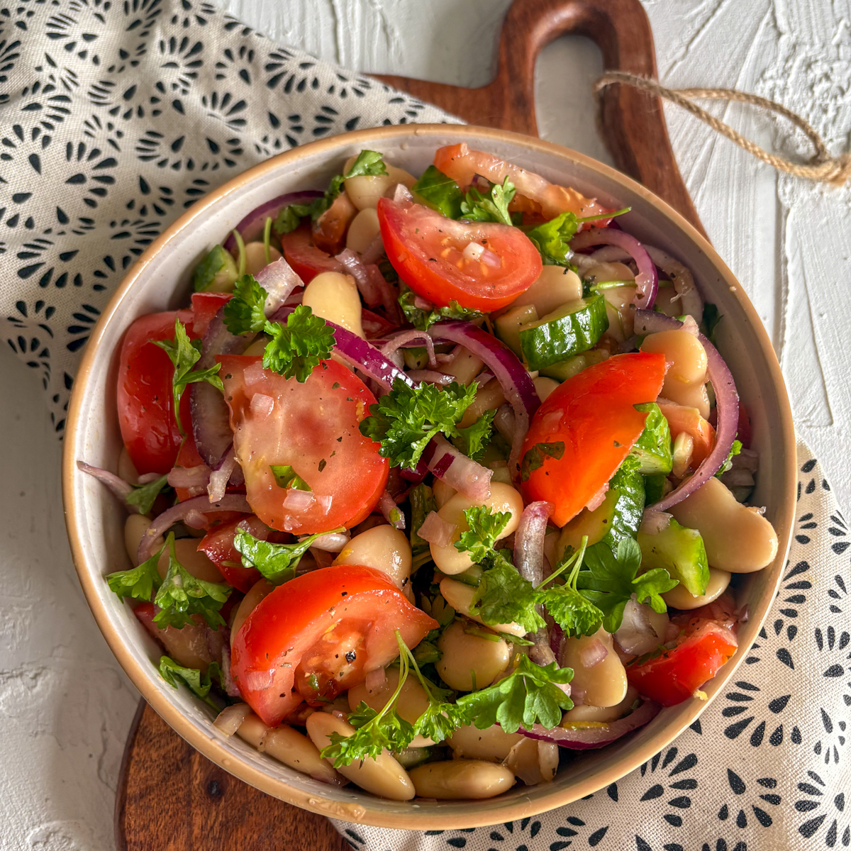 A colourful quick summer salad with butter beans and cucumber beautifully presented with a patterned napkin.