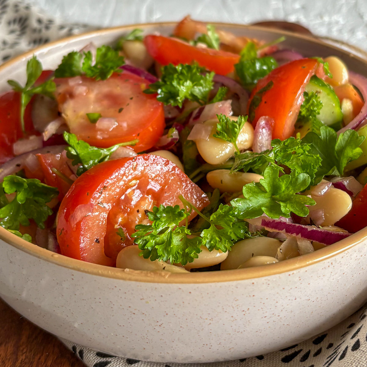Close-up of a white bean and tomato salad showing the texture of creamy beans and crunchy cucumbers.