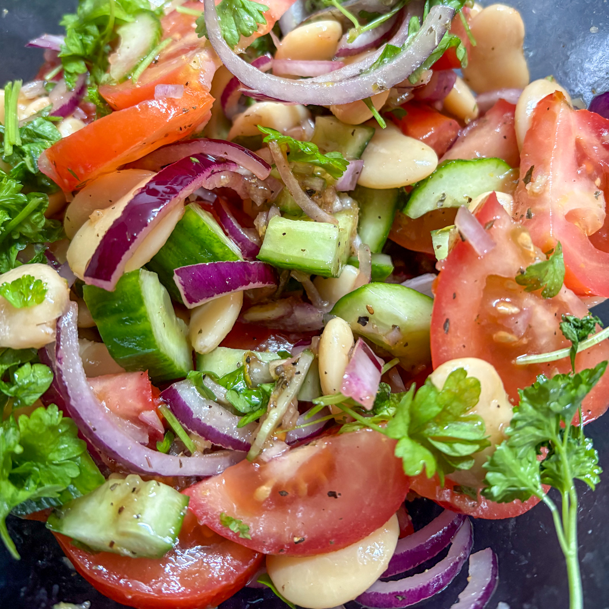 Tossing the butter bean salad to ensure everything is coated in zippy dressing.