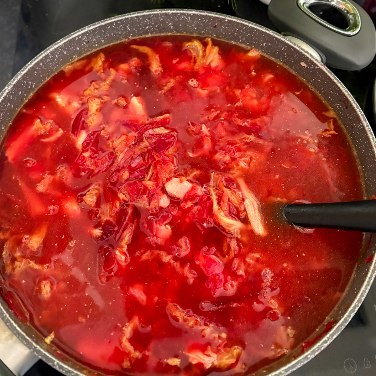 A large stock pot filled with simmering Chicken Borscht showing a deep ruby-red colour and tender vegetables.
